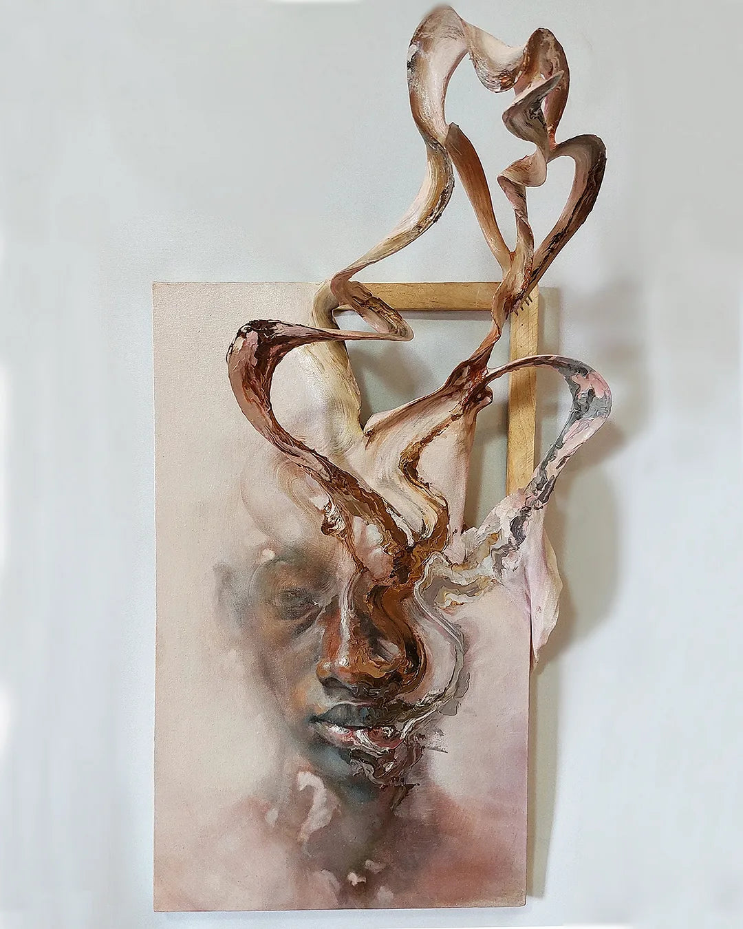 Mixed-media wall work by Fernando M. Mattar in which twisting sculptural forms extend from a painted face.