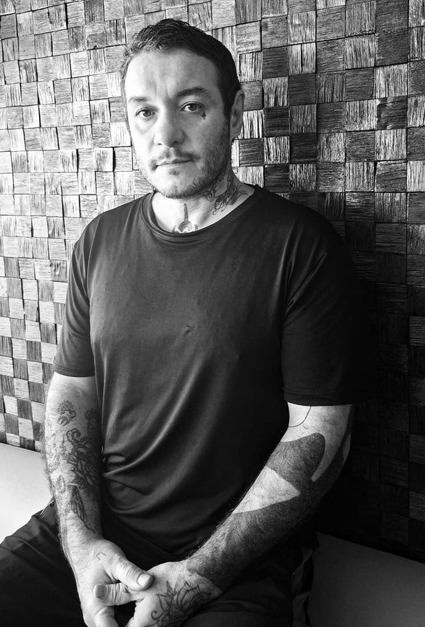 Fernando M. Mattar in a black T-shirt, photographed in front of a woven wood wall.