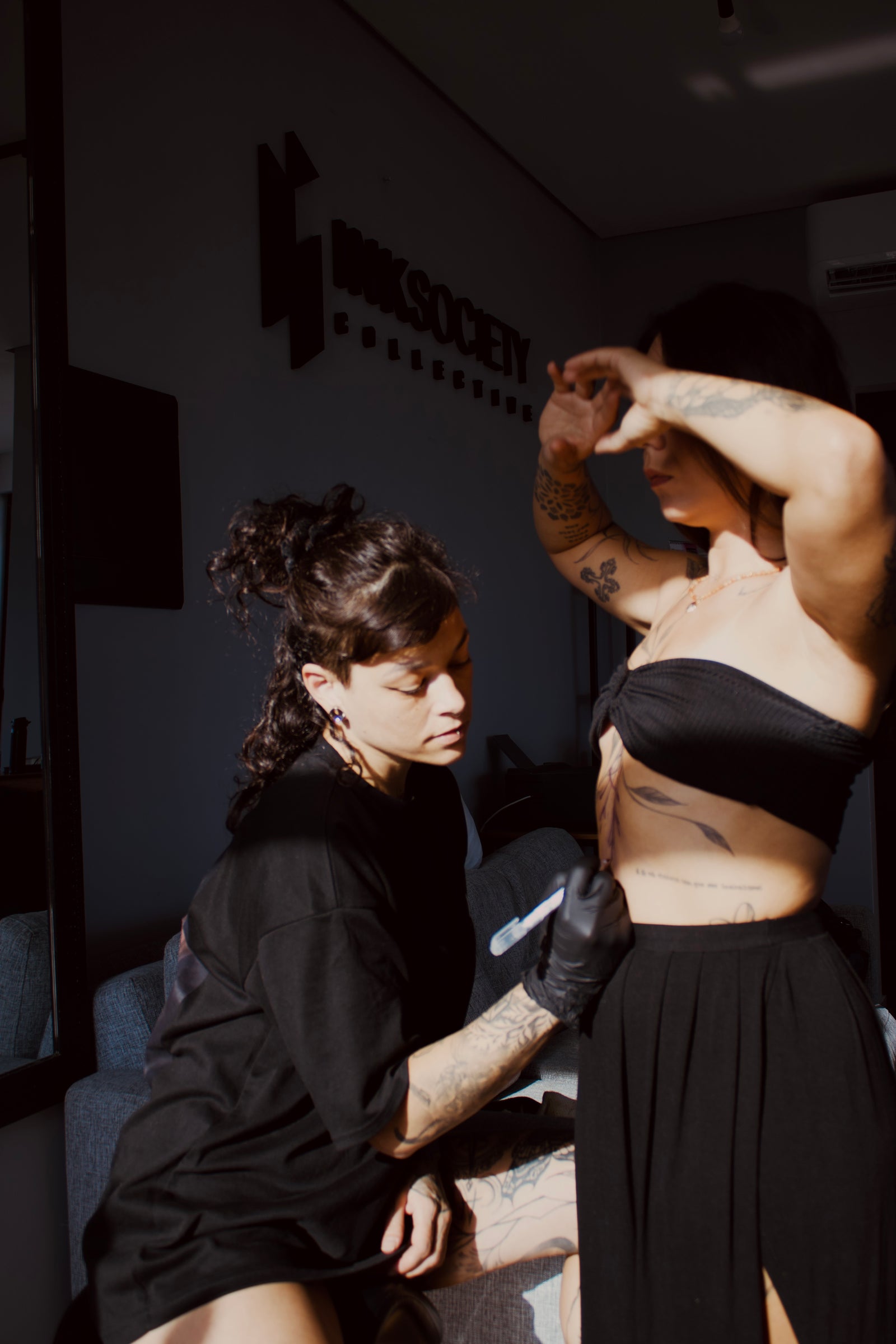 Lua tattooing a client, showing her practice as an active tattoo artist.