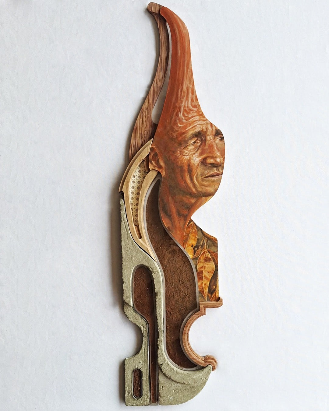 Vertical mixed-media wall relief by Fernando M. Mattar combining a painted profile with layered organic forms.